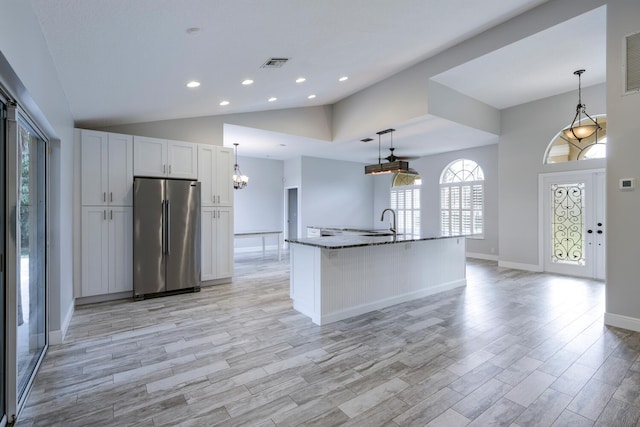 kitchen featuring a center island with sink, white cabinetry, stainless steel fridge, and pendant lighting