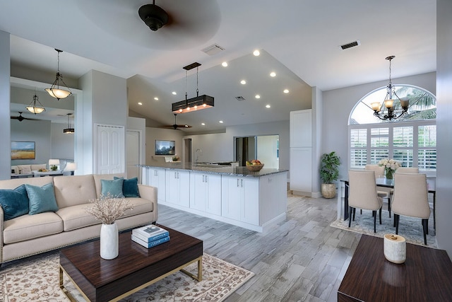 living room with high vaulted ceiling, light hardwood / wood-style flooring, and a chandelier