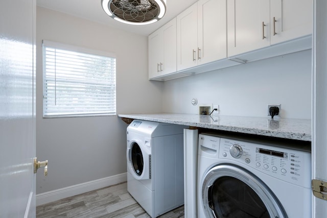 washroom with cabinets, light hardwood / wood-style flooring, and washing machine and clothes dryer