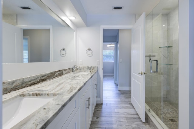 bathroom featuring a shower with door and vanity