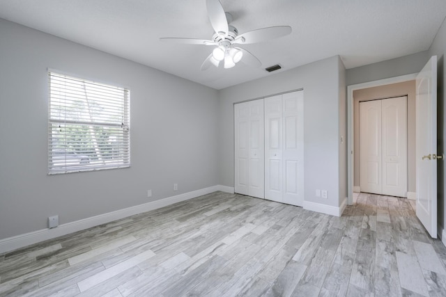 unfurnished bedroom with light wood-type flooring, ceiling fan, and a closet