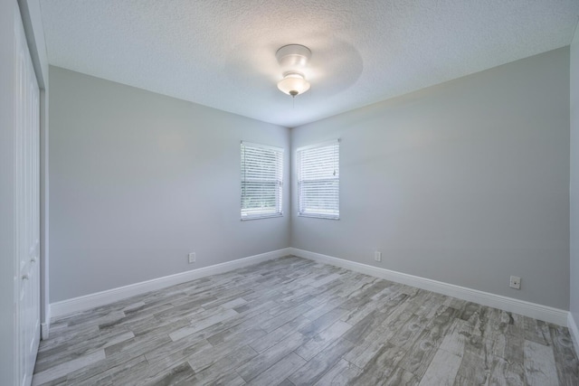 unfurnished room featuring a textured ceiling, light hardwood / wood-style flooring, and ceiling fan