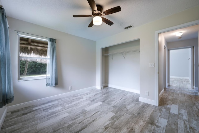 unfurnished bedroom featuring ceiling fan, a textured ceiling, wood-type flooring, and a closet