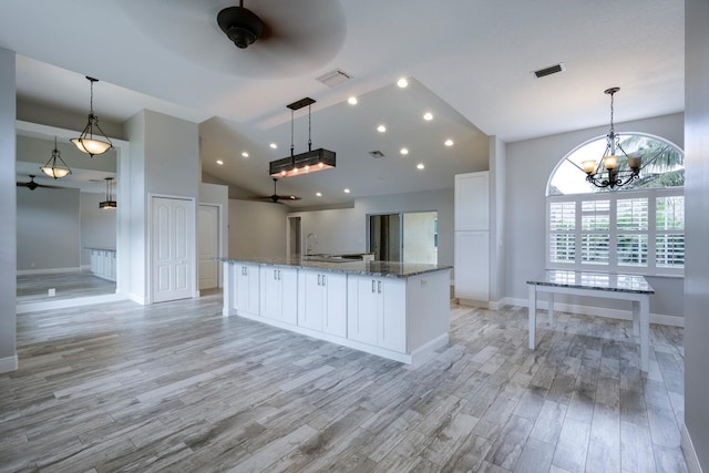 kitchen with white cabinets, light wood-type flooring, light stone counters, and pendant lighting