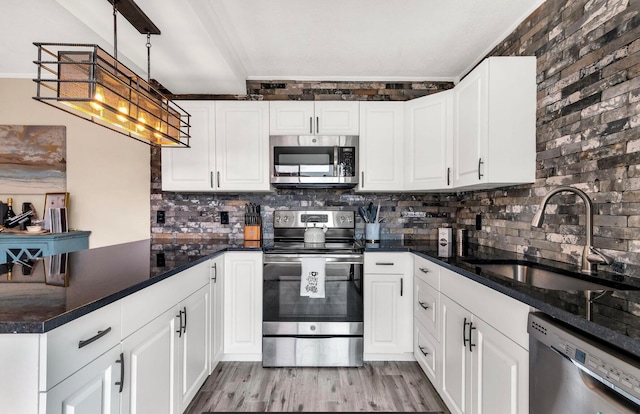 kitchen featuring decorative light fixtures, white cabinetry, sink, and appliances with stainless steel finishes