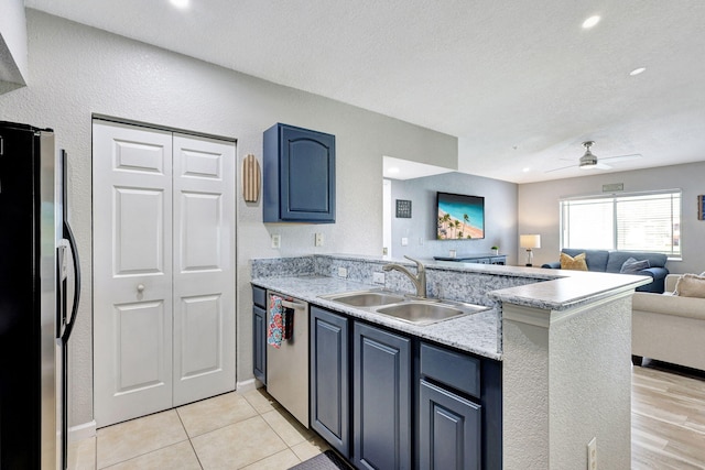 kitchen featuring sink, ceiling fan, blue cabinetry, kitchen peninsula, and stainless steel appliances