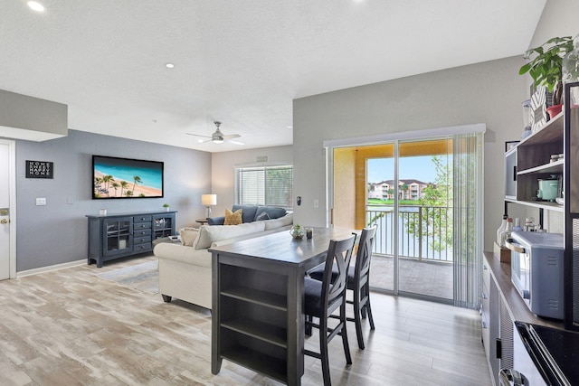 dining area with a textured ceiling, light hardwood / wood-style floors, and ceiling fan