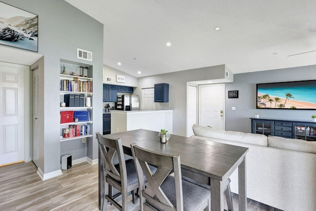 dining room featuring built in features, light hardwood / wood-style flooring, and vaulted ceiling