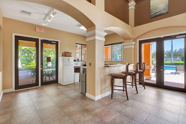 kitchen with french doors, white appliances, rail lighting, and ornate columns