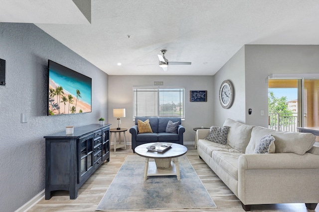 living room featuring ceiling fan, wood-type flooring, and a textured ceiling