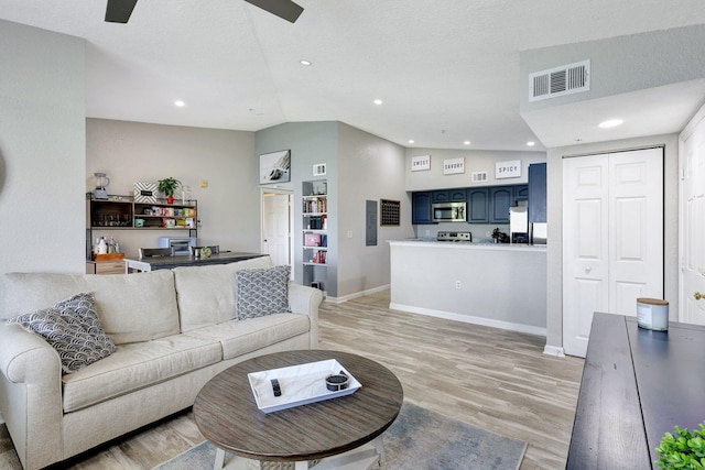 living room with ceiling fan, light hardwood / wood-style floors, lofted ceiling, and a textured ceiling