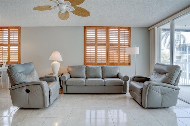 living room featuring ceiling fan, light tile patterned floors, and a textured ceiling