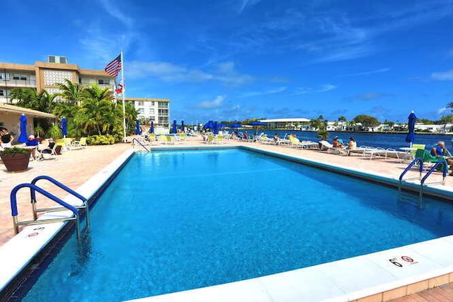 view of swimming pool featuring a patio and a water view