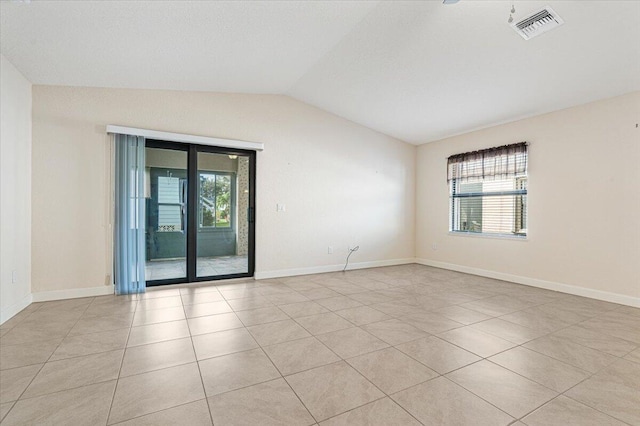 spare room with a wealth of natural light, light tile patterned flooring, and lofted ceiling