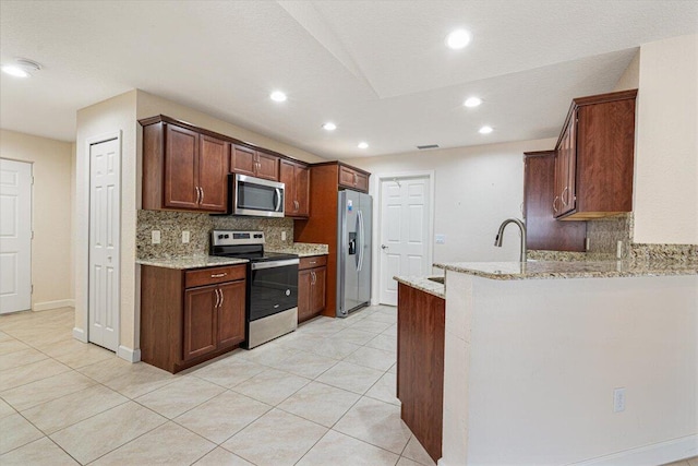 kitchen with backsplash, light stone counters, light tile patterned flooring, and stainless steel appliances