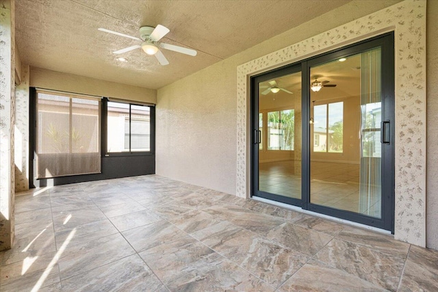 unfurnished sunroom with ceiling fan