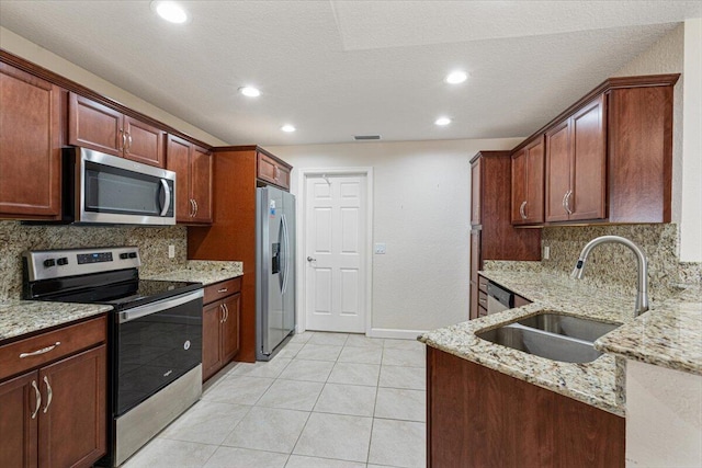 kitchen with light stone countertops, appliances with stainless steel finishes, decorative backsplash, and sink