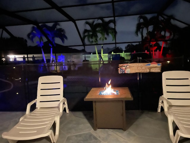 patio at twilight featuring a lanai and an outdoor fire pit