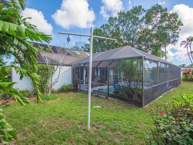 back of property with a yard and a lanai