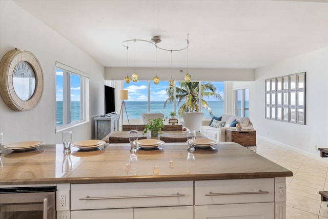 kitchen with light tile patterned floors, decorative light fixtures, beverage cooler, and white cabinets