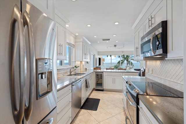 kitchen featuring appliances with stainless steel finishes, white cabinetry, wine cooler, light tile patterned floors, and kitchen peninsula