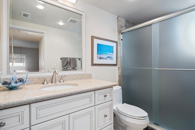 bathroom with a shower with door, vanity, and toilet