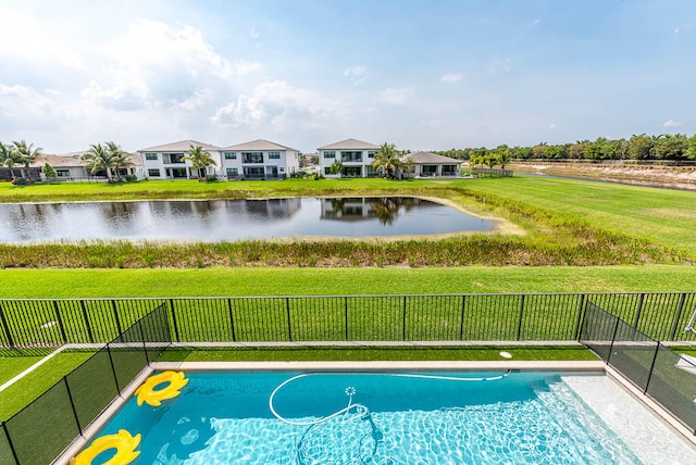 view of swimming pool featuring a lawn and a water view