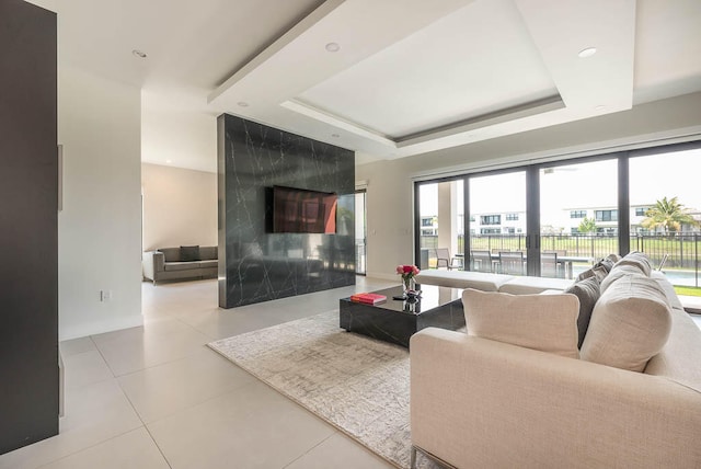 living room with a tray ceiling and a premium fireplace