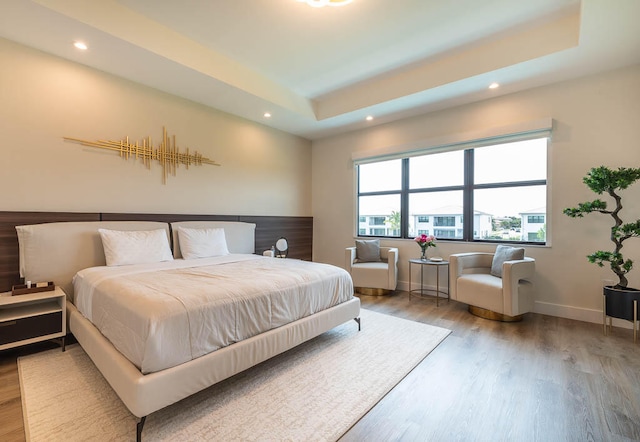 bedroom with wood-type flooring and a tray ceiling