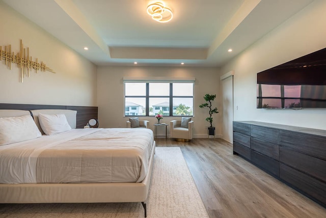 bedroom featuring a tray ceiling and light hardwood / wood-style floors