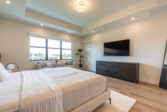 bedroom with a raised ceiling and light hardwood / wood-style flooring