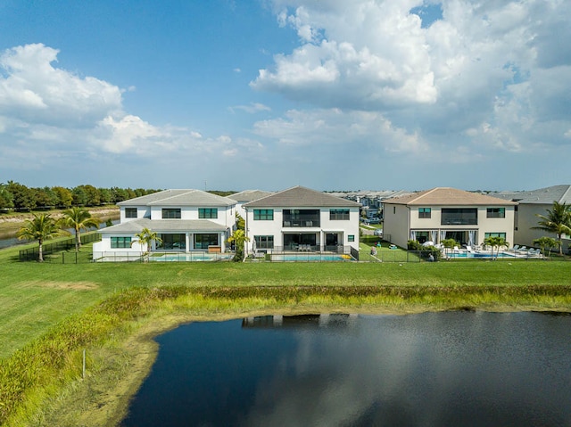 rear view of property with a water view, a lawn, and a swimming pool