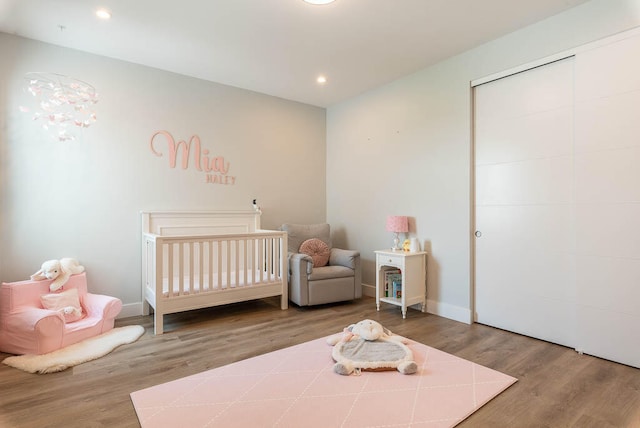 bedroom featuring a closet, hardwood / wood-style floors, and a crib