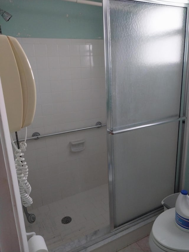 bathroom featuring tile patterned floors, toilet, and walk in shower