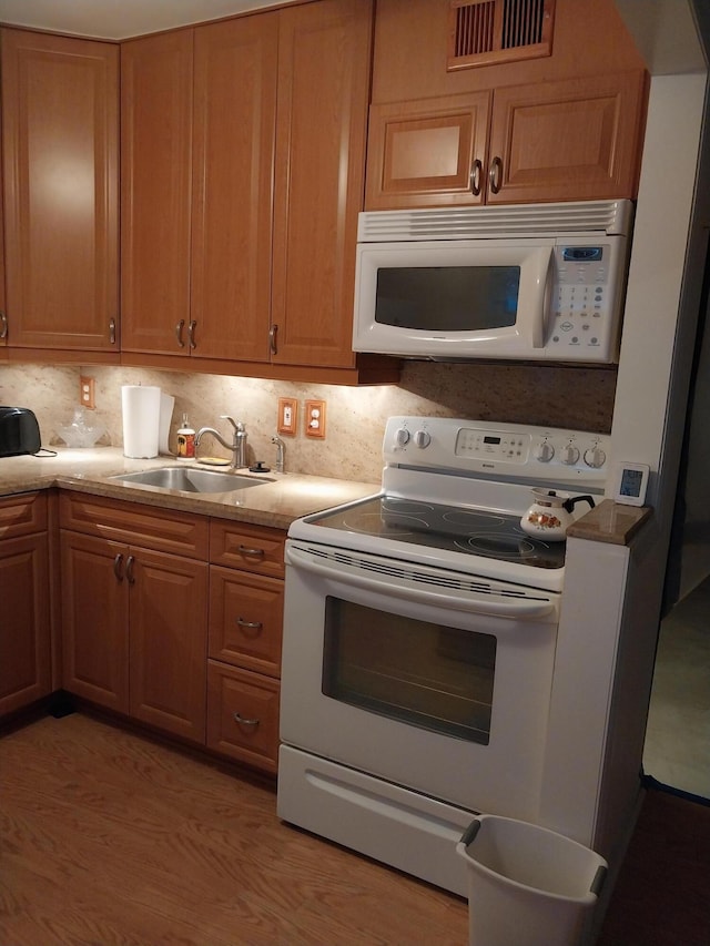 kitchen featuring decorative backsplash, sink, light hardwood / wood-style floors, and white appliances