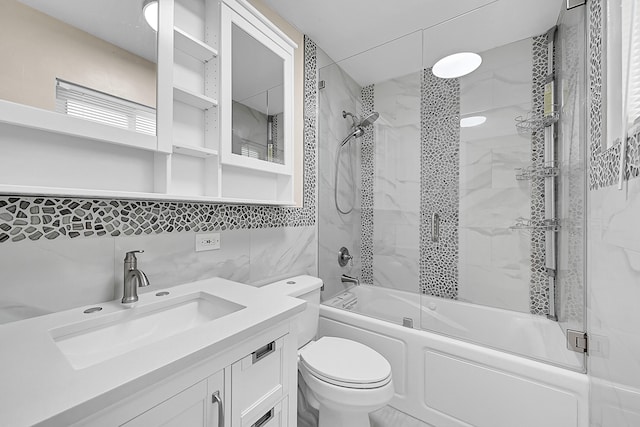 full bathroom with combined bath / shower with glass door, backsplash, toilet, vanity, and tile walls