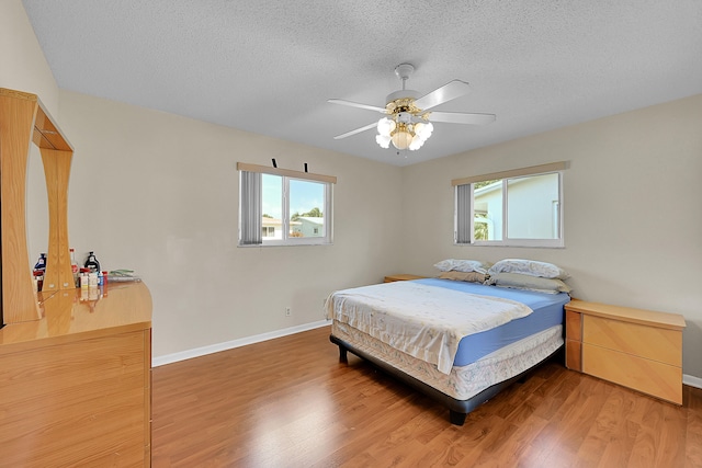 bedroom featuring ceiling fan, wood-type flooring, and a textured ceiling