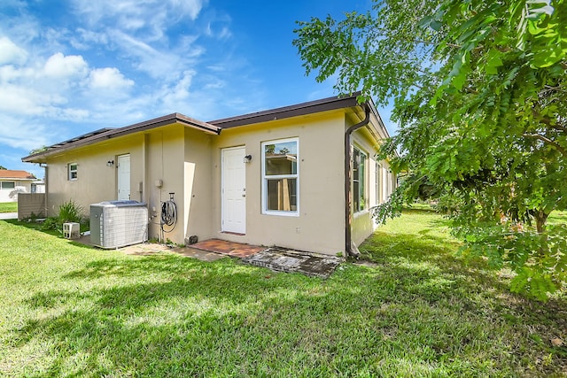 rear view of property featuring a lawn and cooling unit