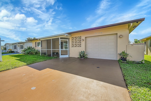 view of front of property with a sunroom, a front yard, and a garage