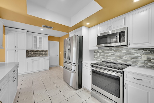 kitchen featuring backsplash, white cabinets, stainless steel appliances, and light tile patterned floors