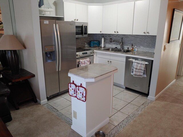 kitchen with a center island, sink, stainless steel appliances, decorative backsplash, and white cabinets