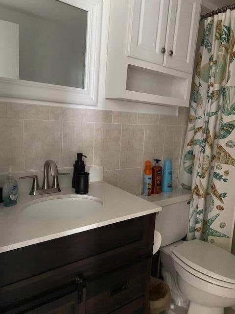 bathroom with tasteful backsplash, vanity, and toilet