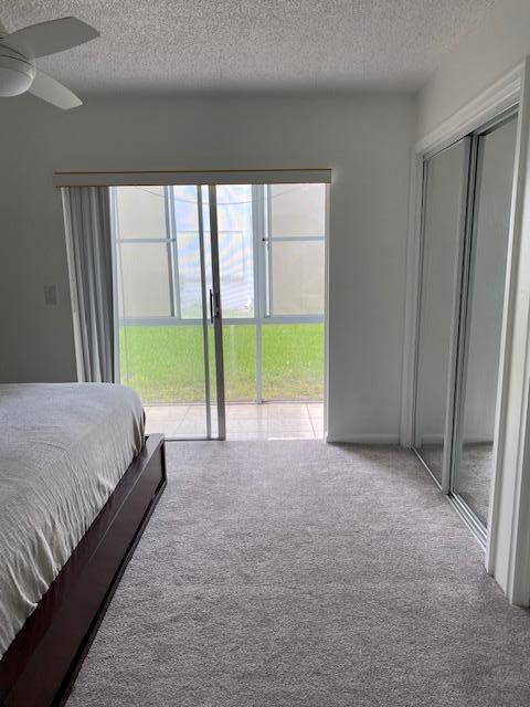 unfurnished bedroom with ceiling fan, light colored carpet, and a textured ceiling