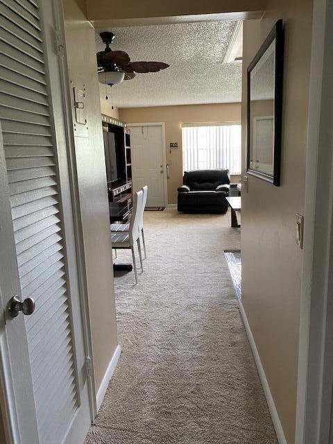 hall featuring light colored carpet and a textured ceiling