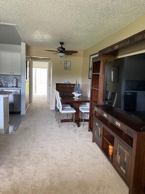 carpeted living room with a textured ceiling and ceiling fan