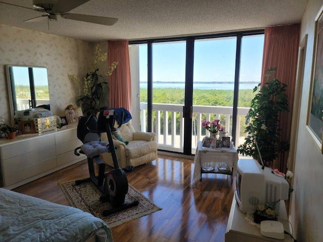 bedroom featuring wallpapered walls, floor to ceiling windows, wood finished floors, and a textured ceiling