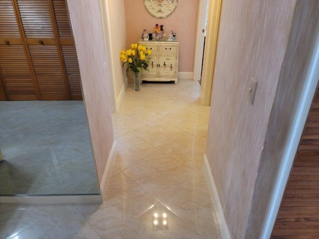 hall featuring light tile patterned flooring and baseboards