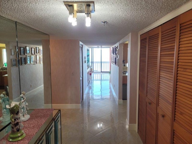 corridor featuring a wall of windows, baseboards, and a textured ceiling