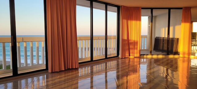 spare room with a wealth of natural light, a water view, and a wall of windows