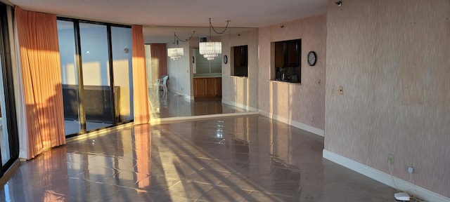 spare room featuring baseboards, wallpapered walls, floor to ceiling windows, a notable chandelier, and marble finish floor